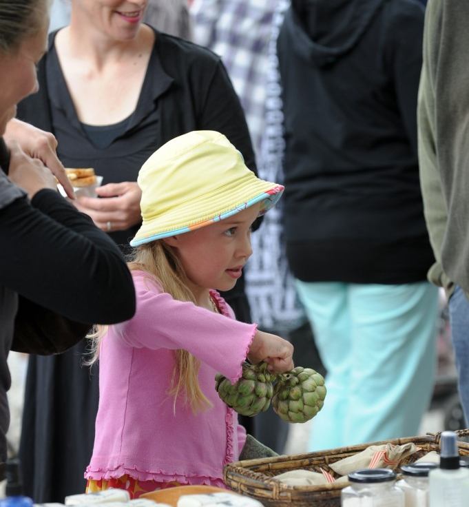 Girl buying artichokes at a market